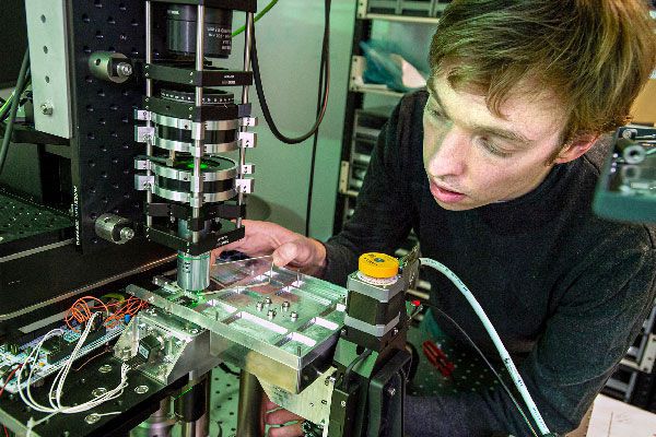 Scientist loads piece of glass into machine 